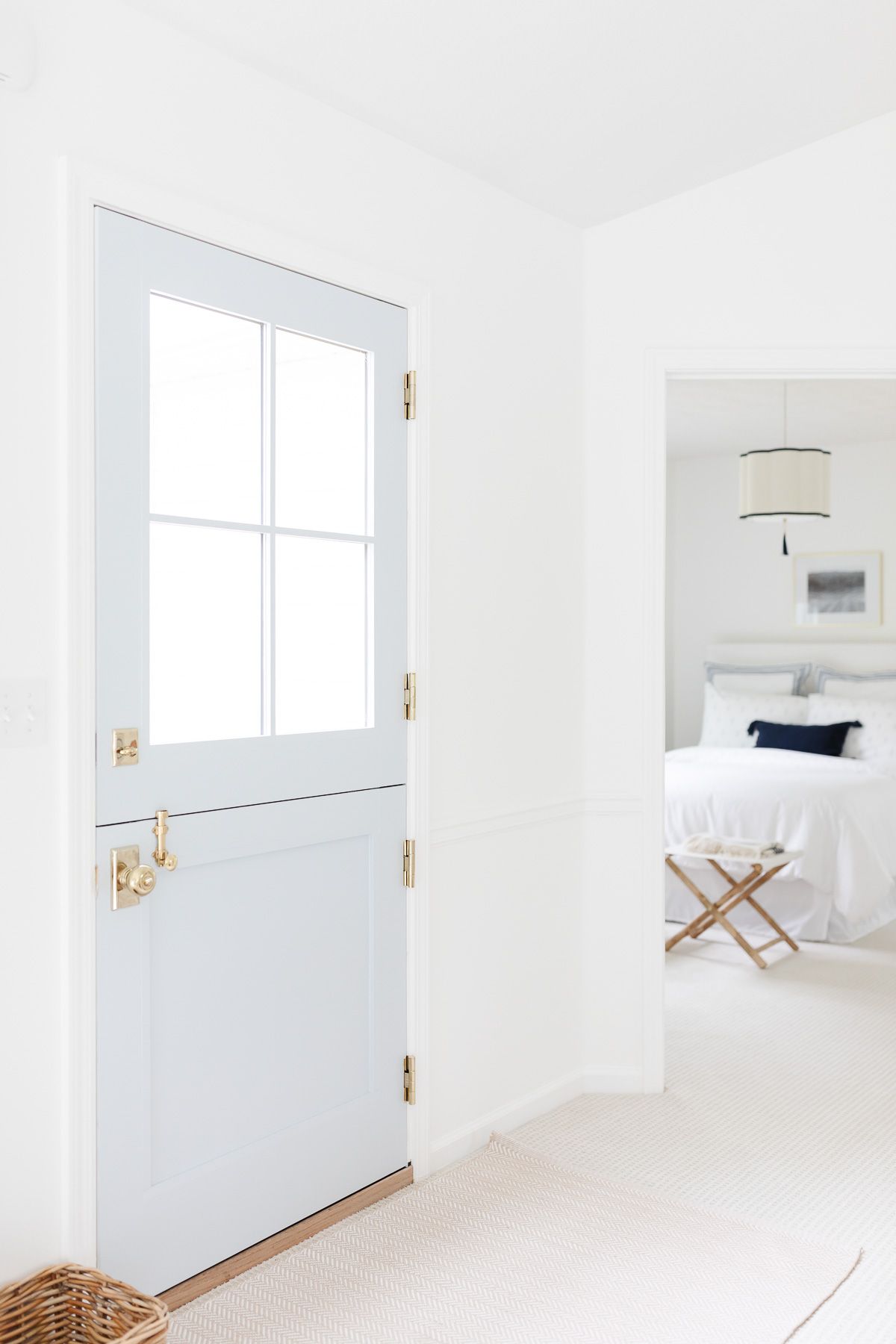 A basket near a coastal blue dutch door in a white living room