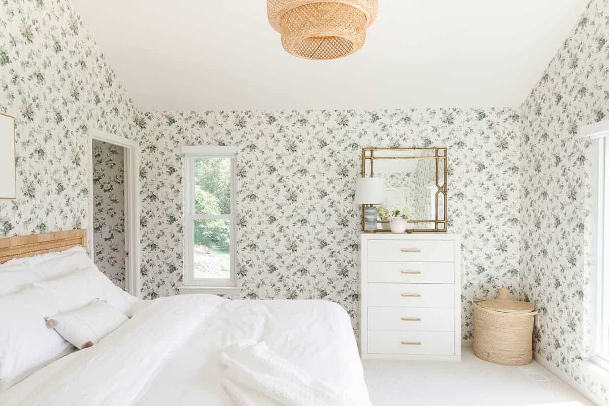 wallpapered bedroom with white dresser and brass pulls