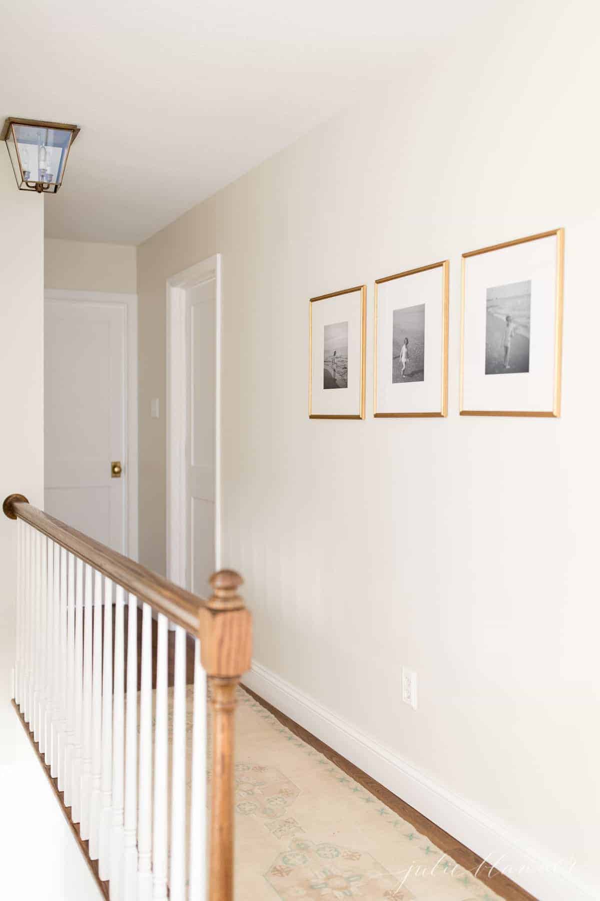 A cream hallway with hardwood floors, in a tutorial for how to paint trim white.