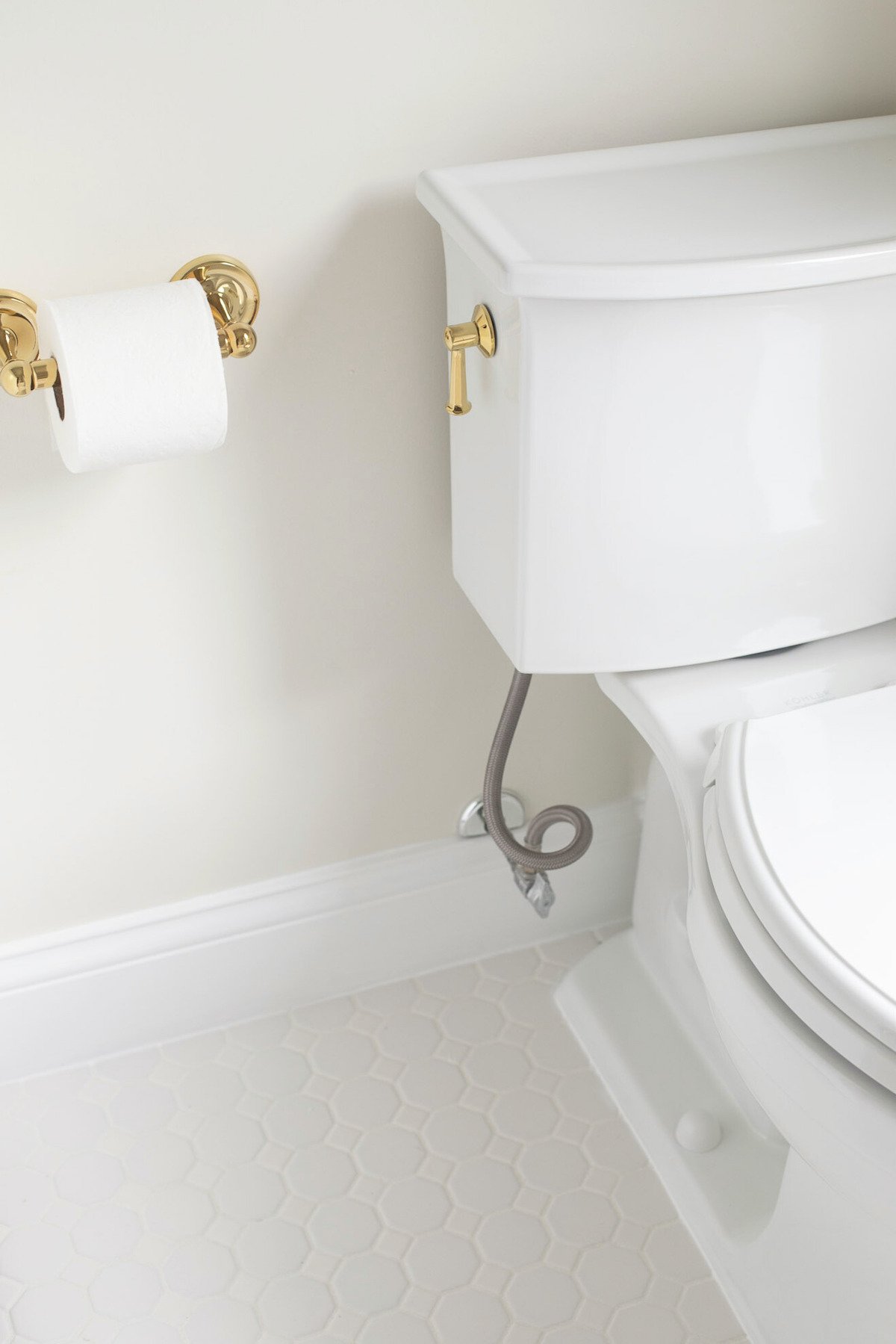 A white toilet in a white bathroom, as part of a guide to painting trim white. 