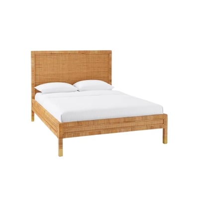 A stunning rattan bed with white sheets and wooden legs exudes comfort and style.