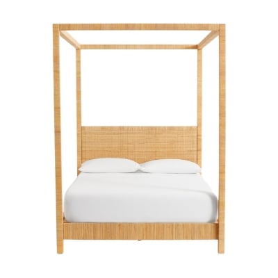 A rattan bed with white sheets.
