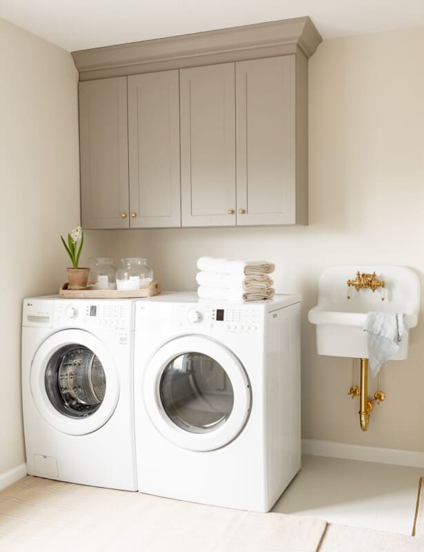 A second floor laundry room with gray cabinets and a small white sink.