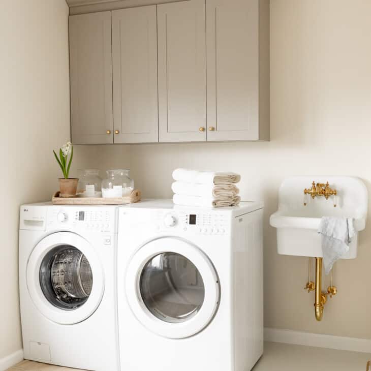 A second floor laundry room with gray cabinets and a small white sink.