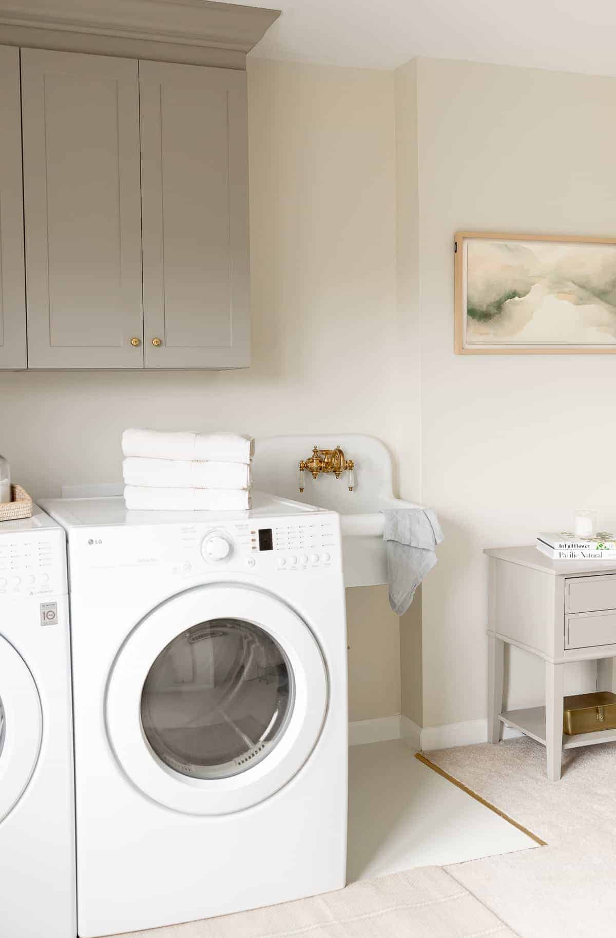 A second floor laundry room with gray cabinets and a small white sink.