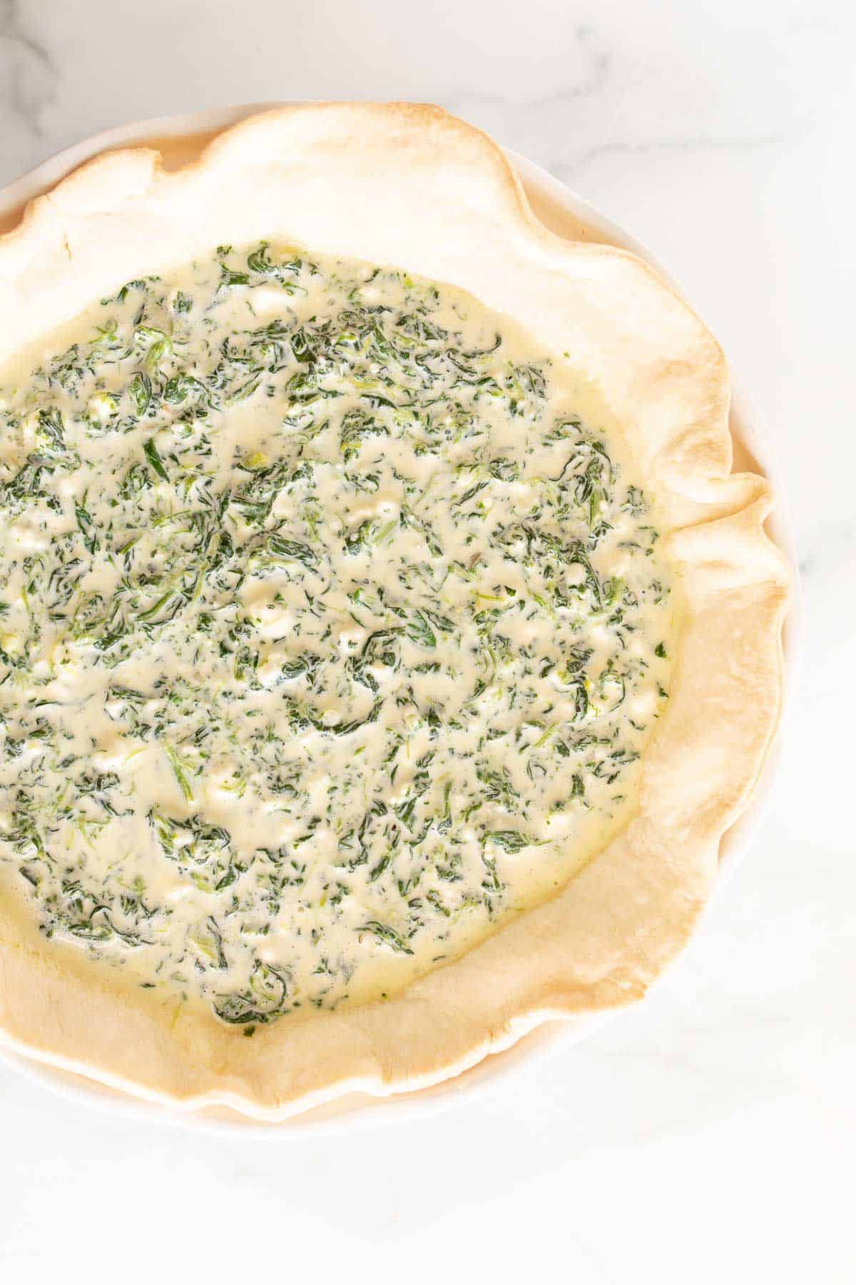 A spinach quiche before it goes in the oven to be baked.