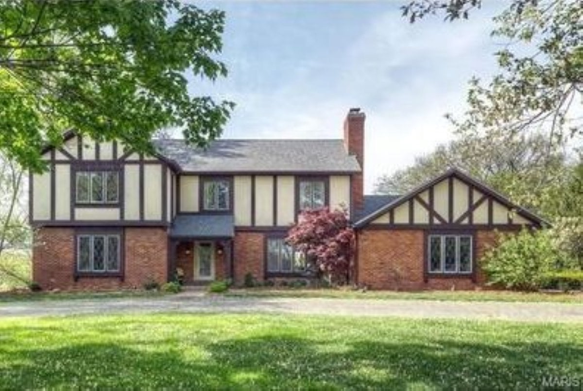 Traditional tudor paint colors on a vintage tudor style home, with brick at the base and pale yellow and brown on the top.