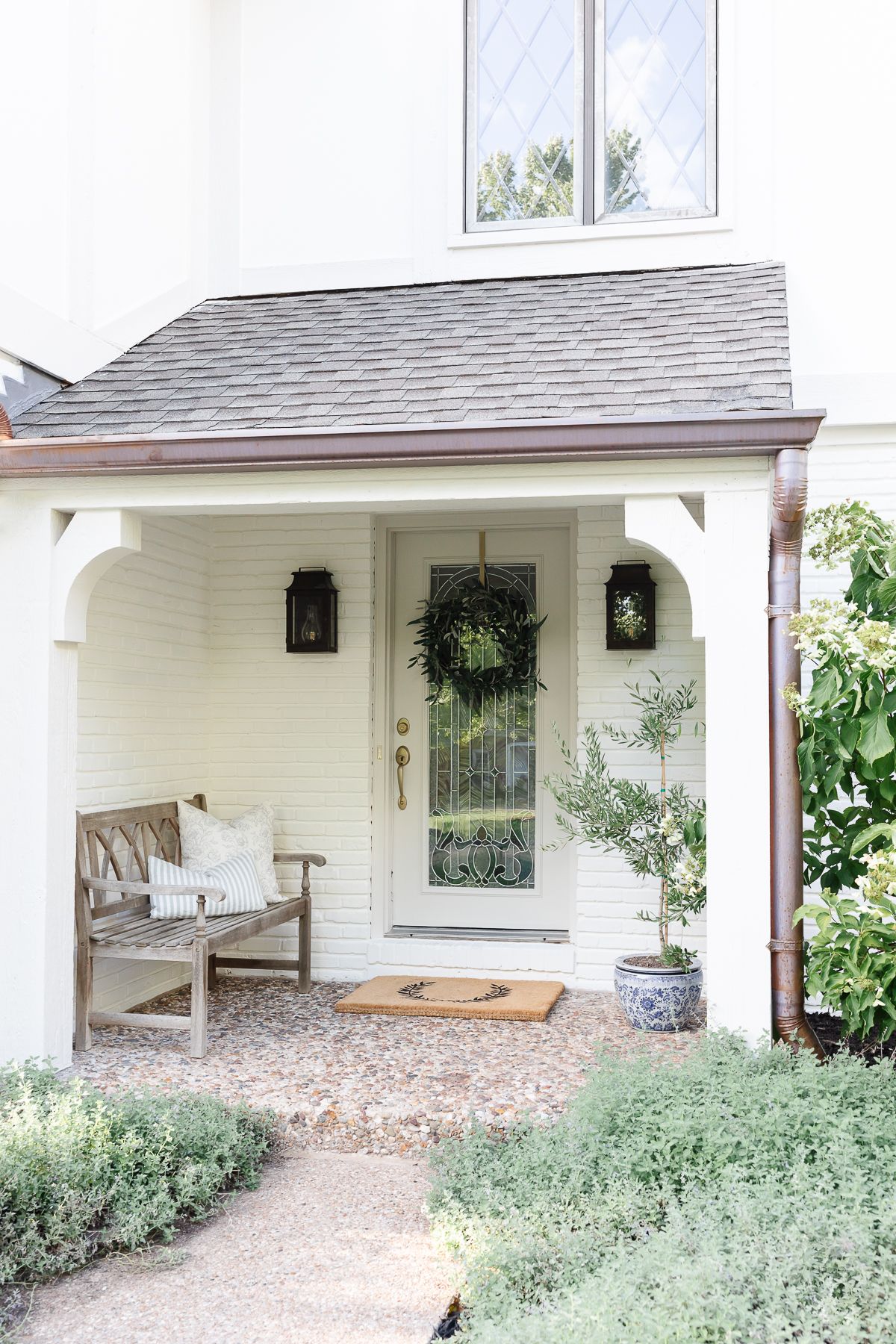 A vintage tudor home entry, painted a cream color with copper guttering.