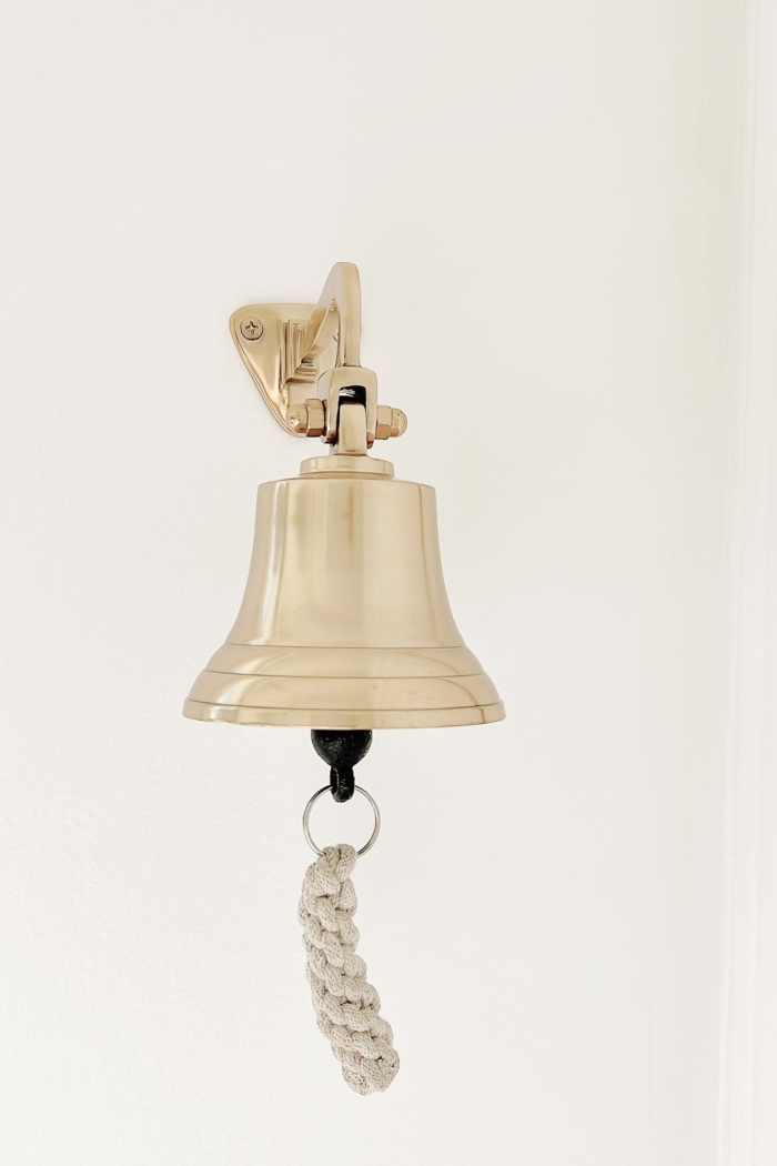 A brass bell hanging on a white wall