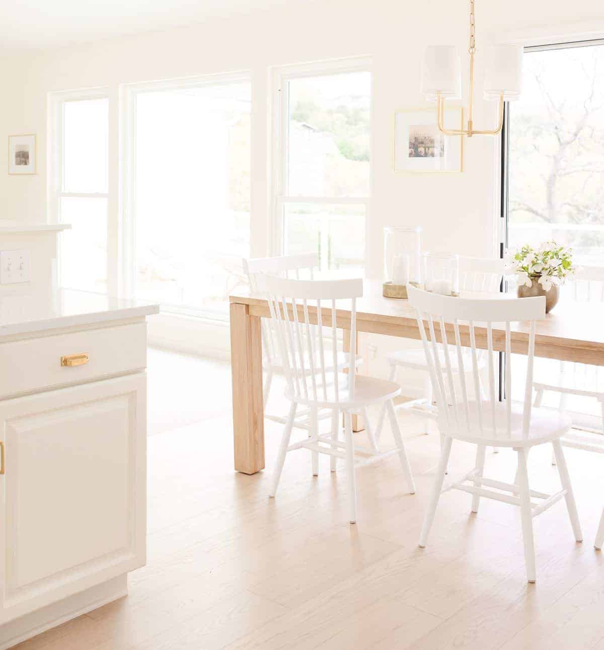A white kitchen dining area with wide white oak floors.