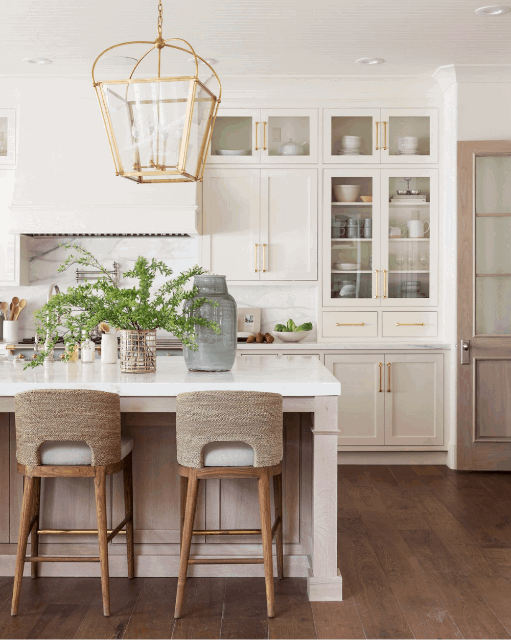 A warm white kitchen painted in Benjamin Moore Swiss Coffee paint color, with a gold lantern above the island.