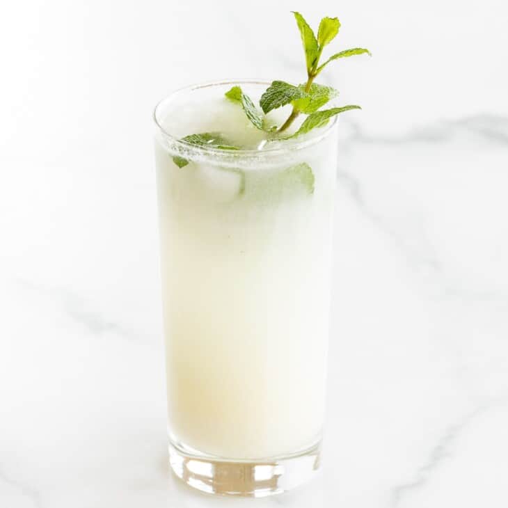 A coconut mojito garnished with mint on a marble surface.