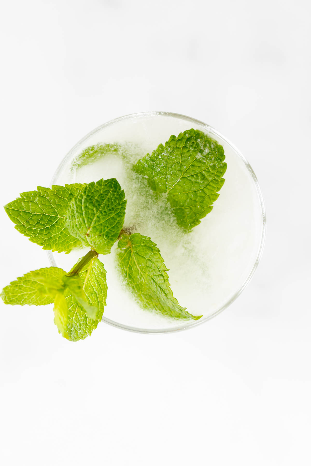 A coconut mojito garnished with mint on a marble surface.
