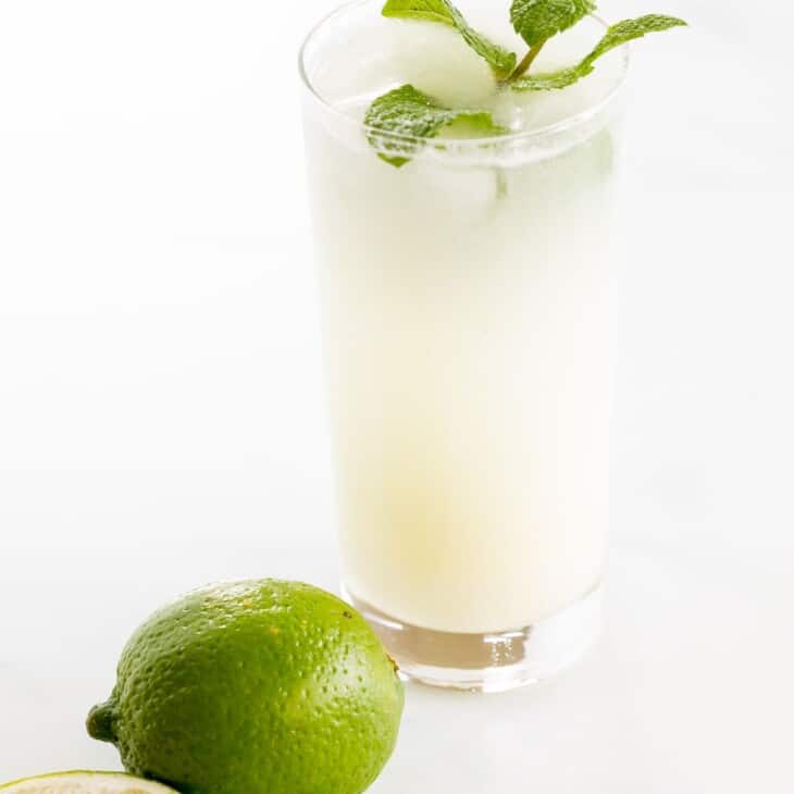 A coconut mojito garnished with mint on a marble surface.