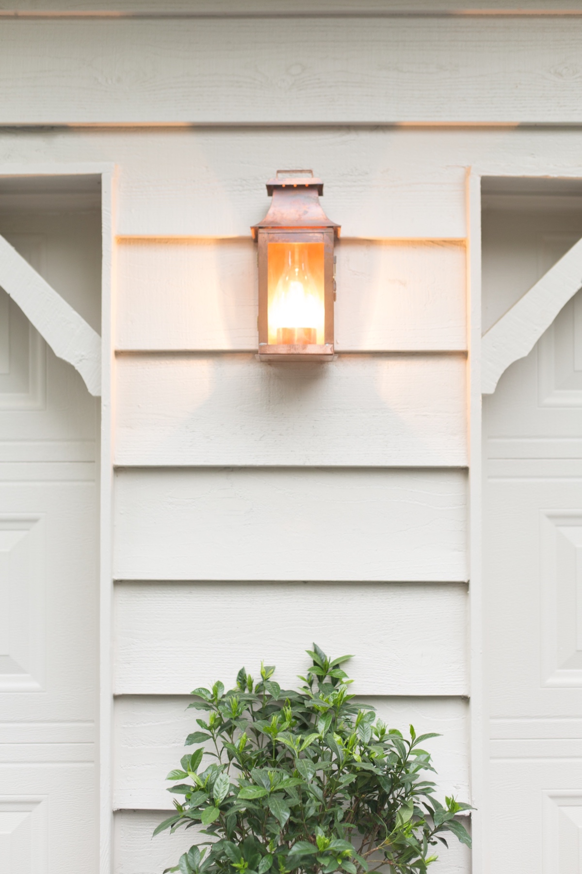 A copper lantern on the white painted exterior of a home.
