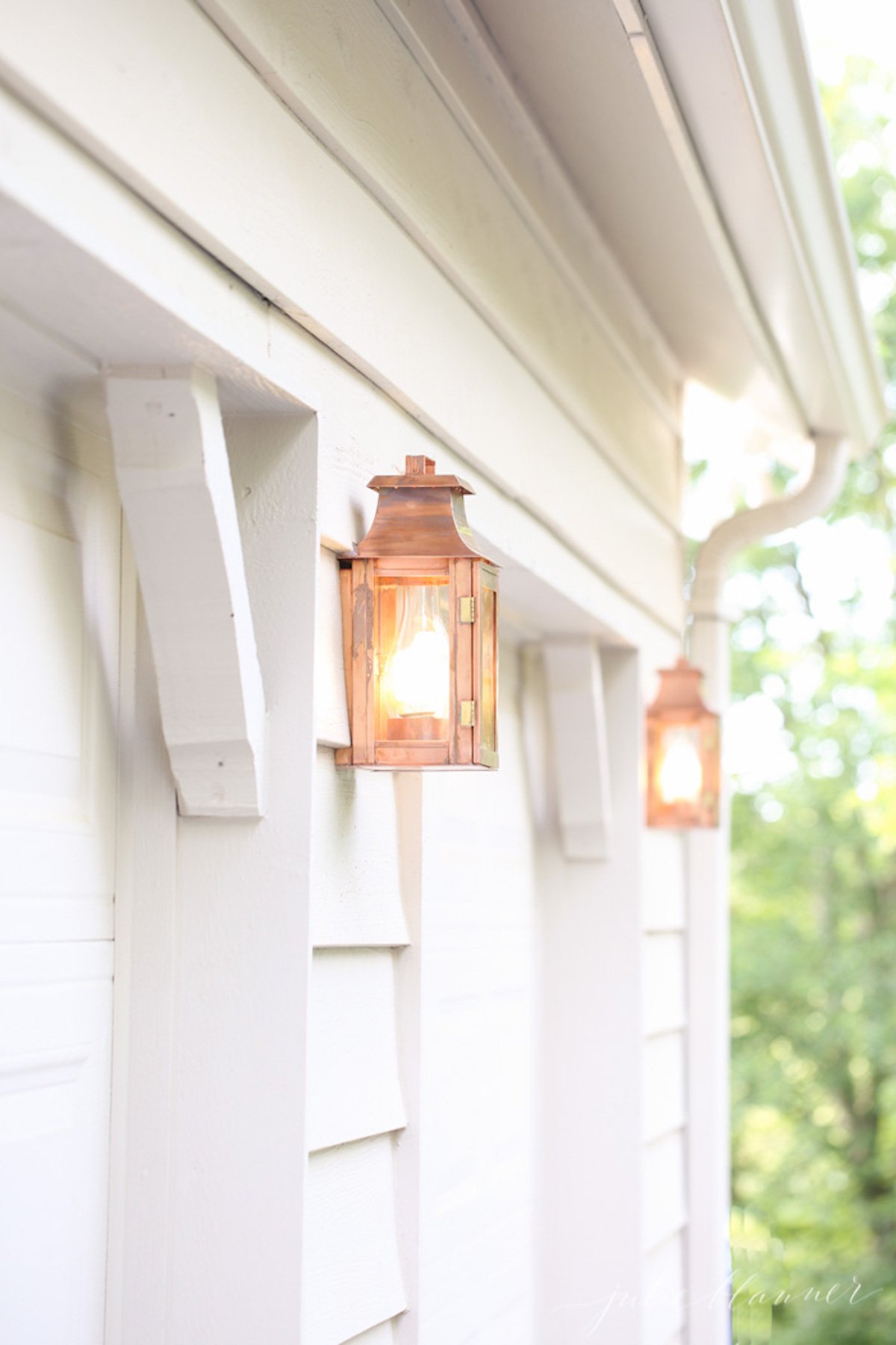 Copper lanterns on the white painted exterior of a home. 