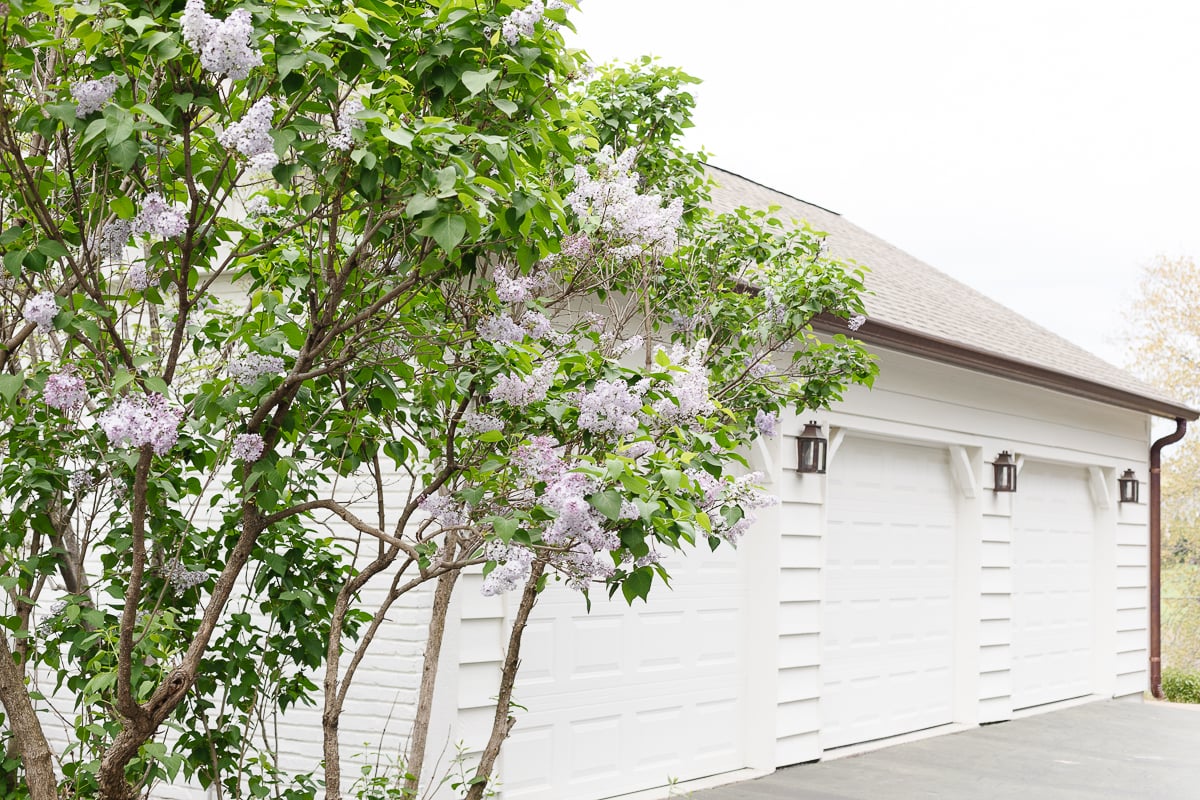A three car garage on a home painted in a soft white color, with copper lanterns.