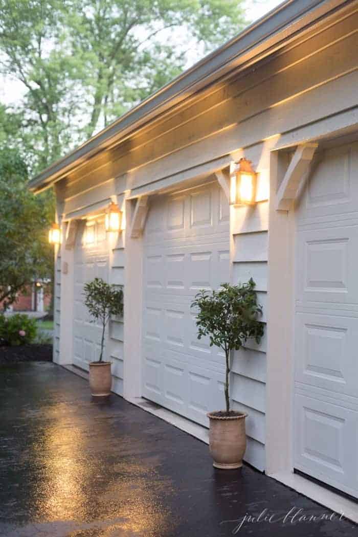 Copper outdoor wall lights on the exterior of a home between garage doors.