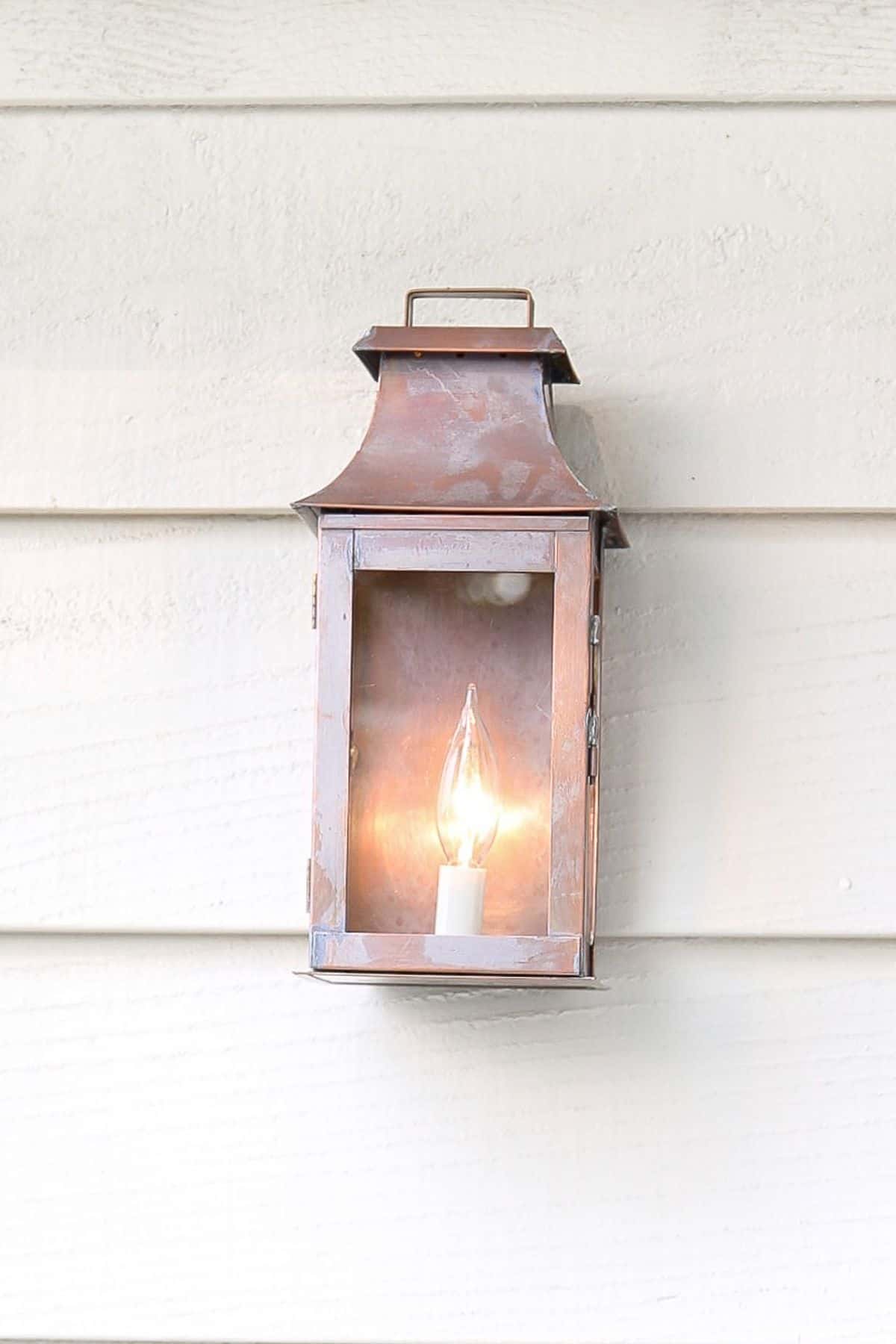 A copper wall lantern on the outside of a house.