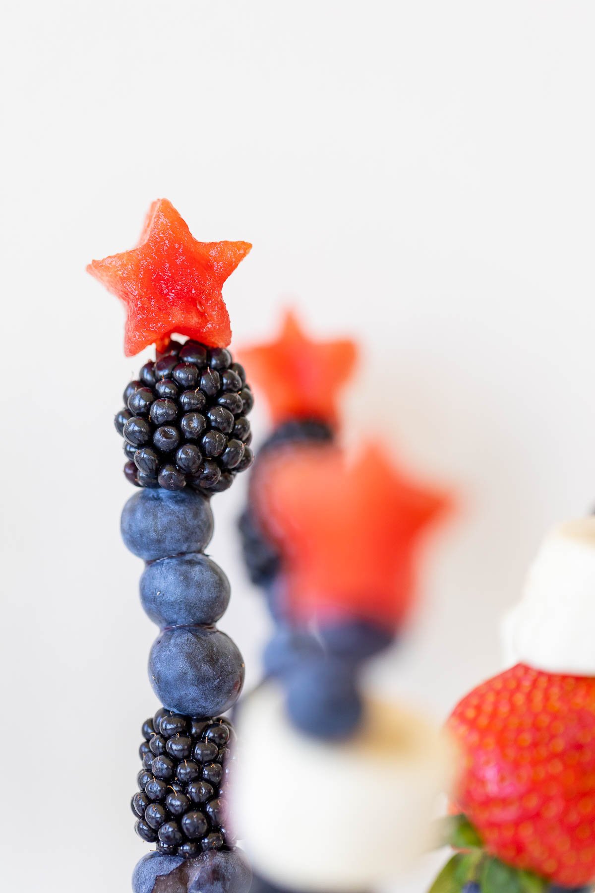 Close up shot of red white and blue fruit skewers with a star on top.