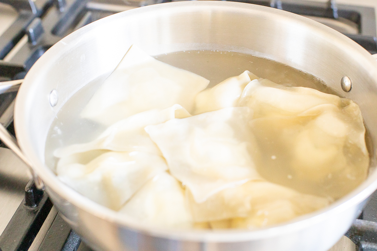 Homemade ravioli cooking in a stainless steel pasta pot.