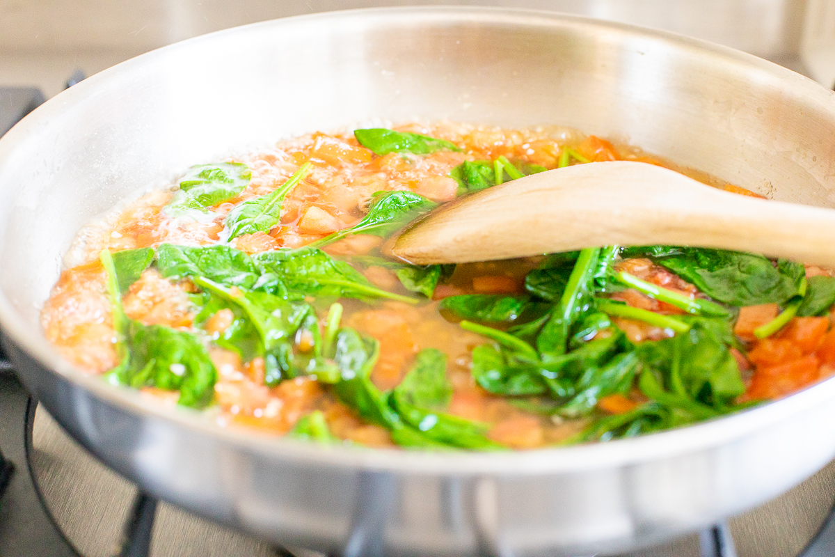 A fresh basil sauce in a stainless steel pot on a stovetop.