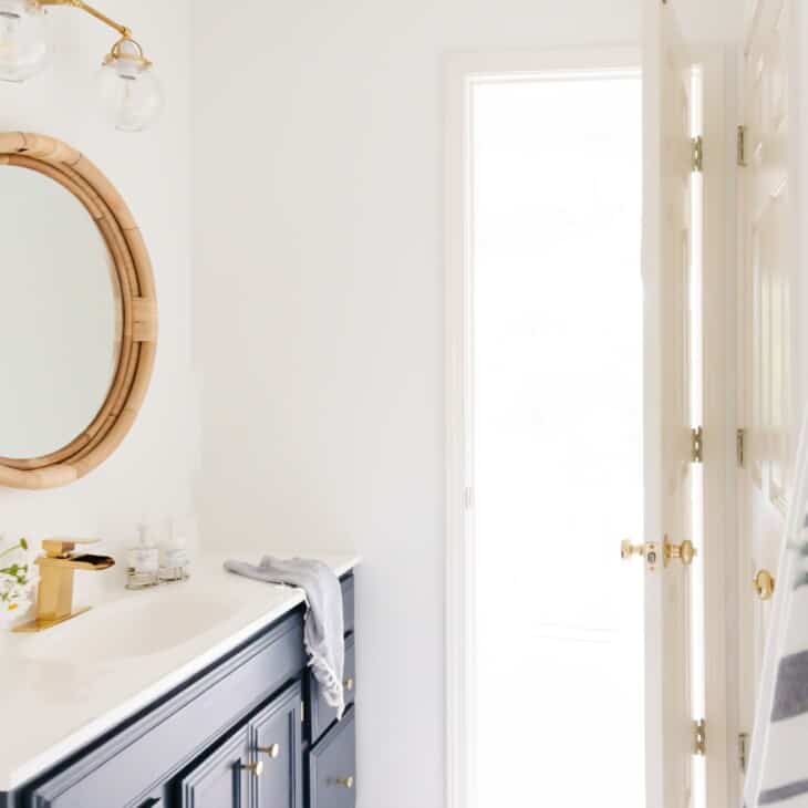 A nautical inspired bathroom with white walls and a wood vanity painted in Benjamin Moore Hale Navy paint color.