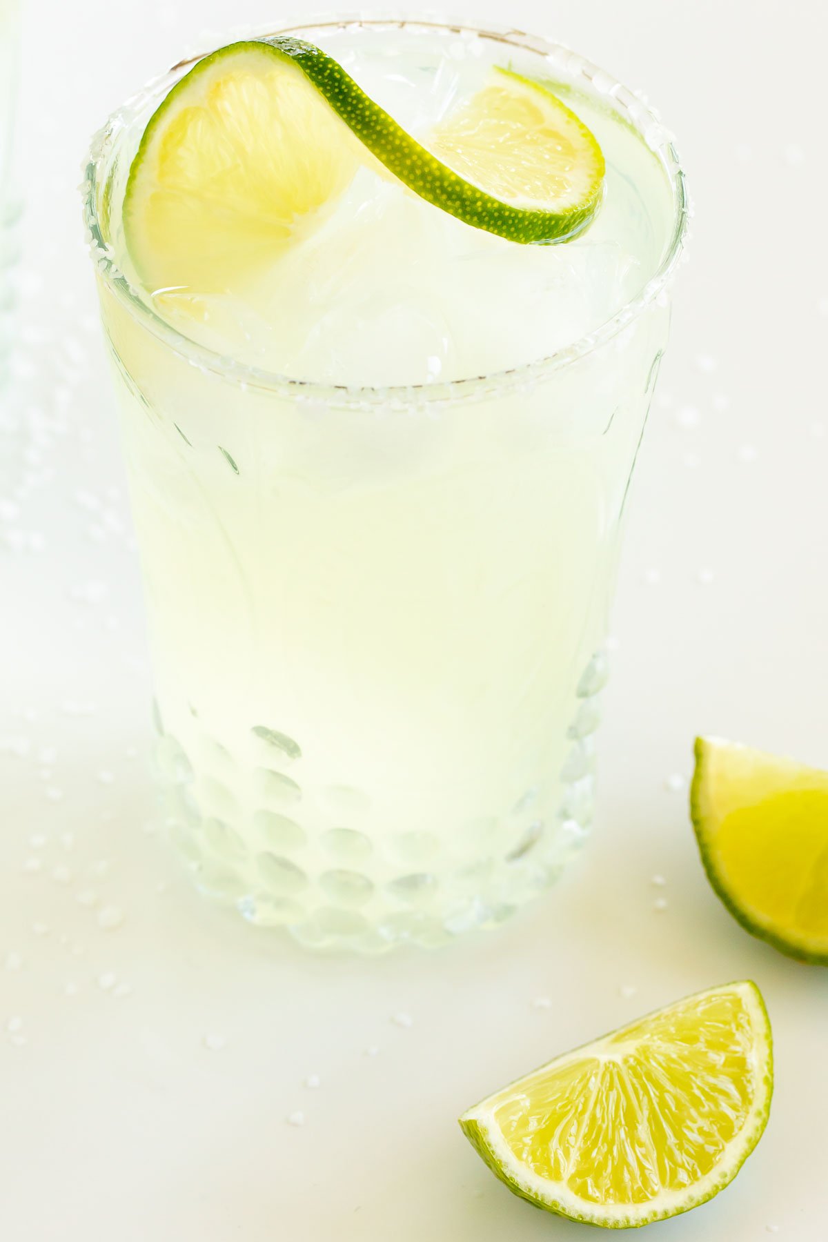 A homemade margarita recipe served up in clear glasses with limes