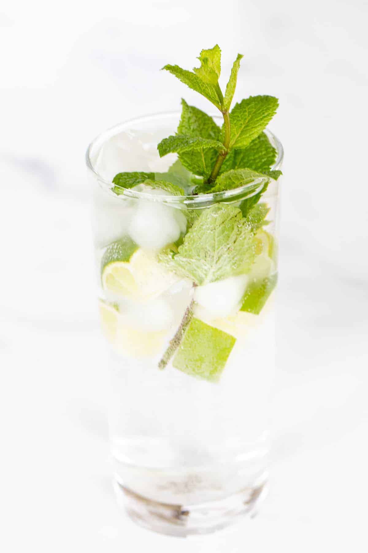 A clear glass full of a non alcoholic mojito recipe on a marble surface.