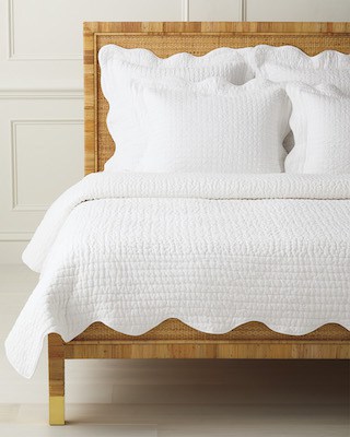 white scalloped quilt on rattan bed