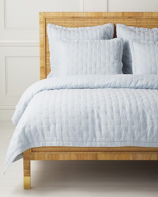 blue tufted quilt on rattan bed