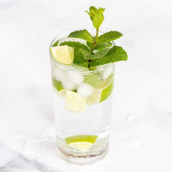 A clear glass full of a virgin mojito recipe on a marble surface.