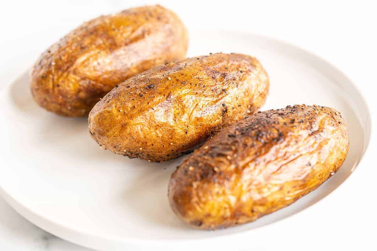 Crispy grilled baked potatoes on a white plate.
