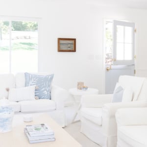 A white living room with blue accents, walls painted in Benjamin Moore Simply White.