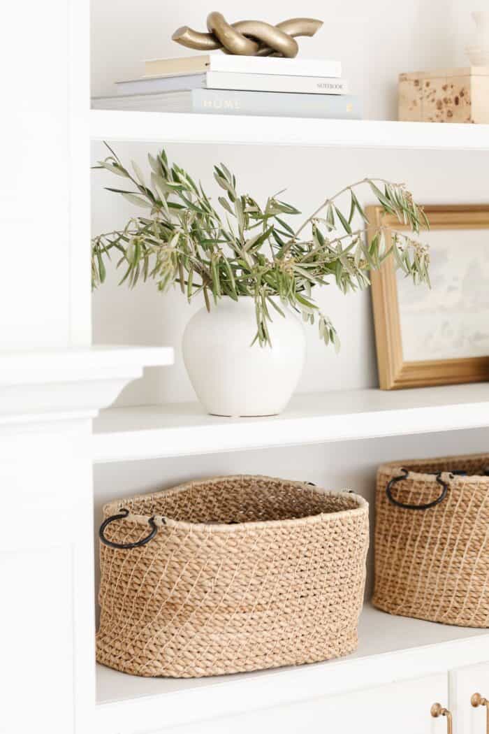 White Built in bookshelves with decor of baskets, white pottery and artwork.