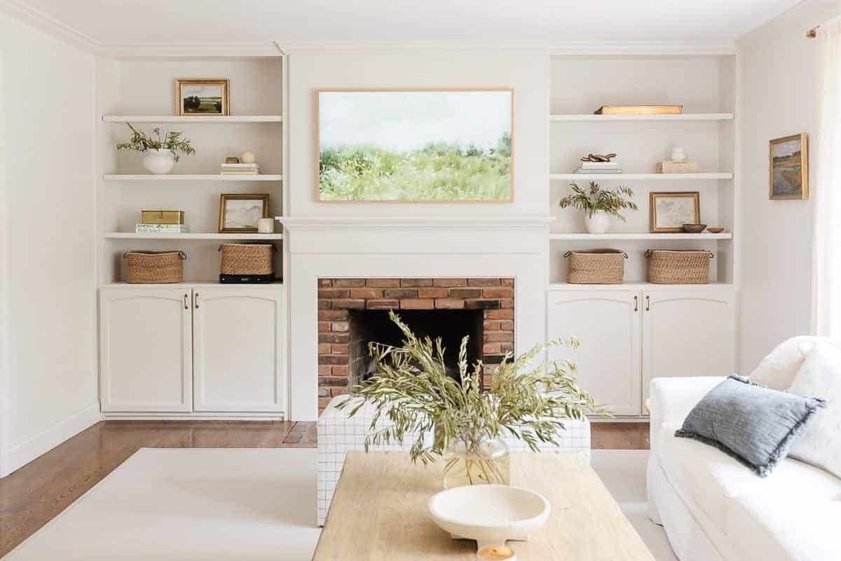 A white living room with bookshelf decor.a brick fireplace surrounded by built ins, 