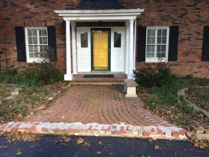 The dark brick entry of a brick home with a yellow door before it was painted white.