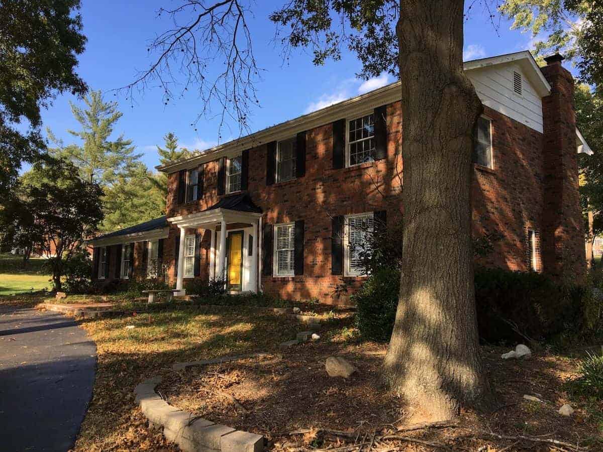 A dark brick house exterior before undergoing a paint transformation.