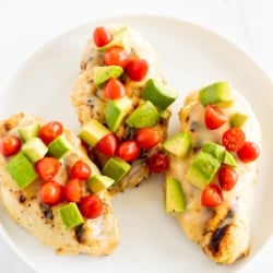 California chicken grill on a white plate, topped with diced avocado and tomato.