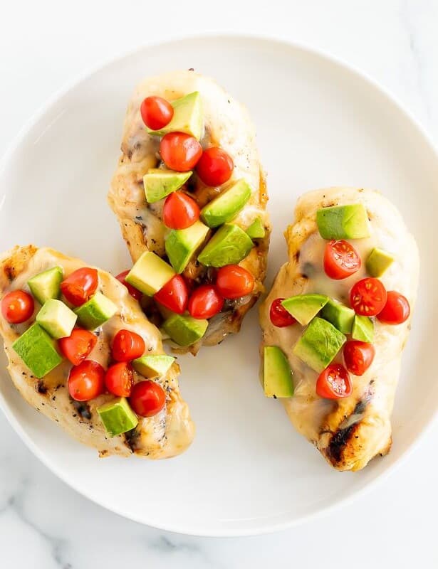 California chicken grill on a white plate, topped with diced avocado and tomato.