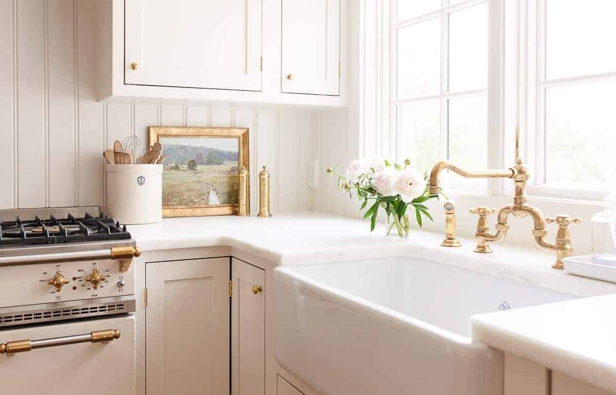 A cream kitchen with a farm sink and custom cabinetry.