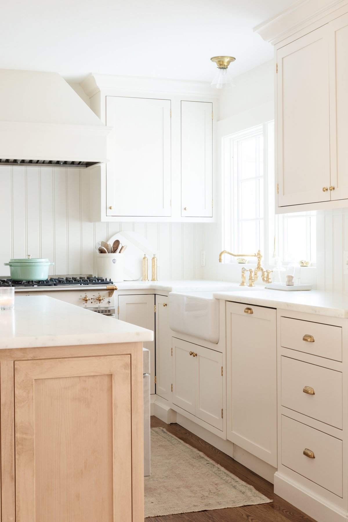 A cream kitchen with custom cabinetry and brass accents.