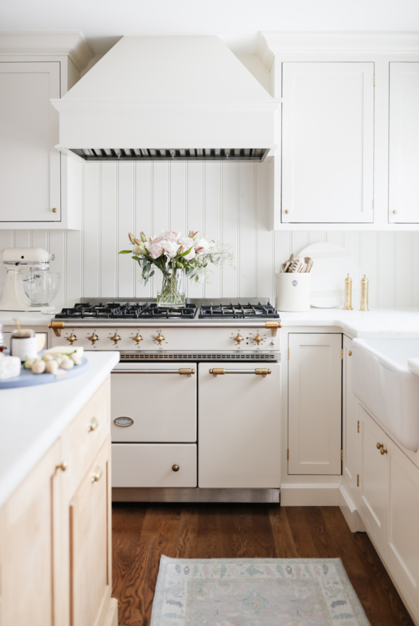 A white kitchen with custom cabinetry and a wooden floor, featuring an oven.