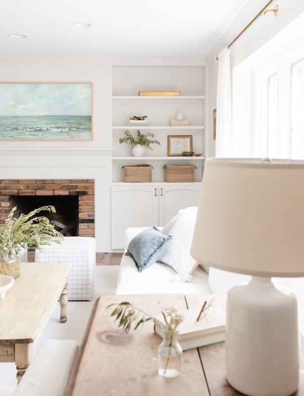 A white living room with bookshelf decor.a brick fireplace surrounded by built ins,