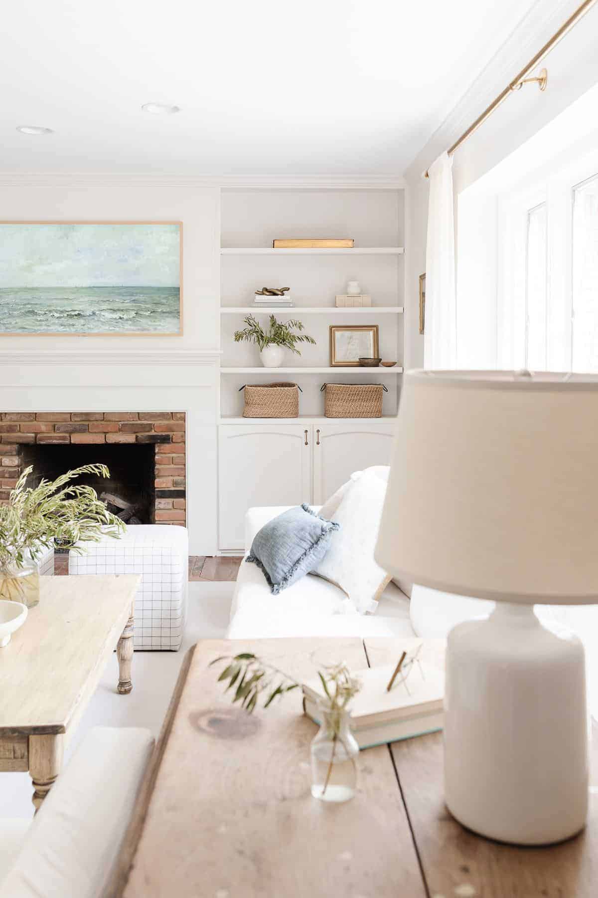 A white living room with bookshelf decor.a brick fireplace surrounded by built ins,