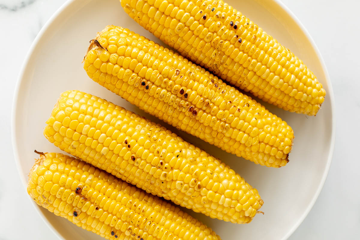 Grilled corn on the cob on a white plate.
