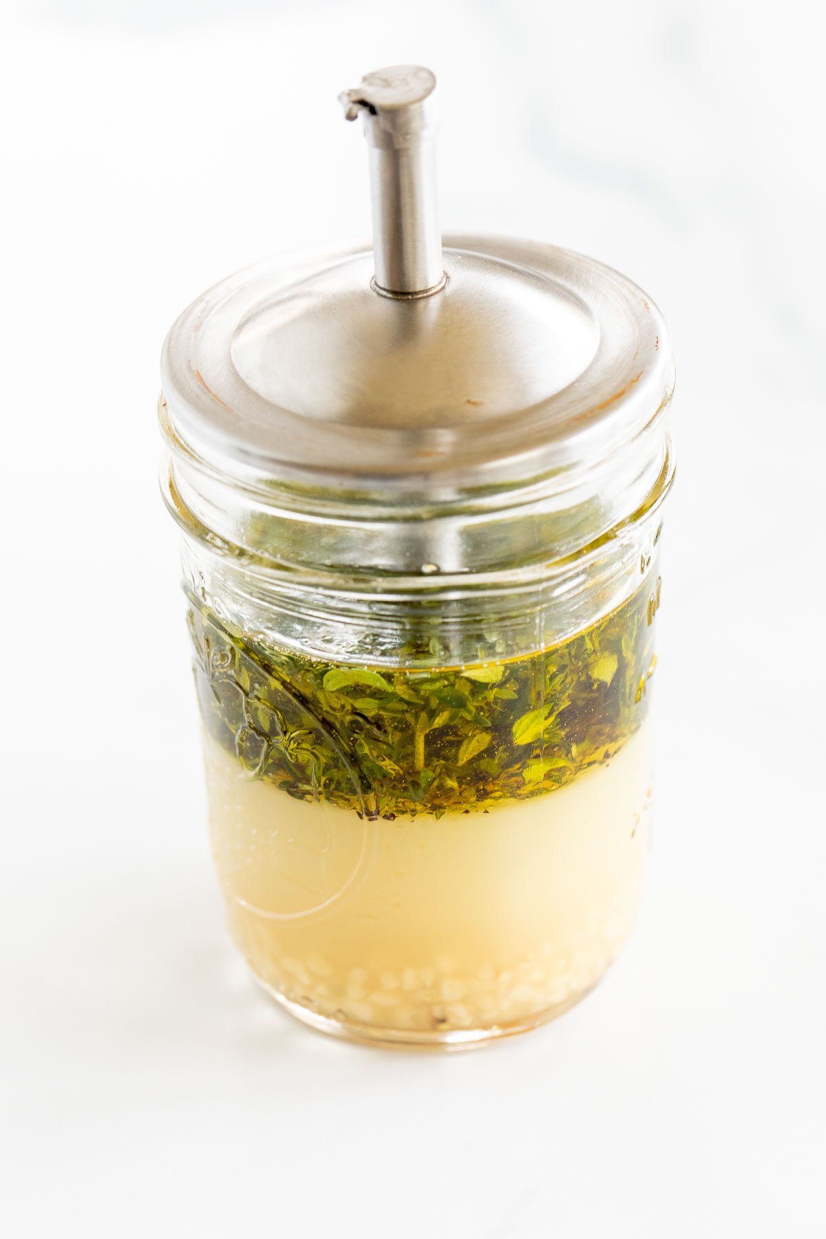 Greek chicken marinade in a glass jar with a silver lid.