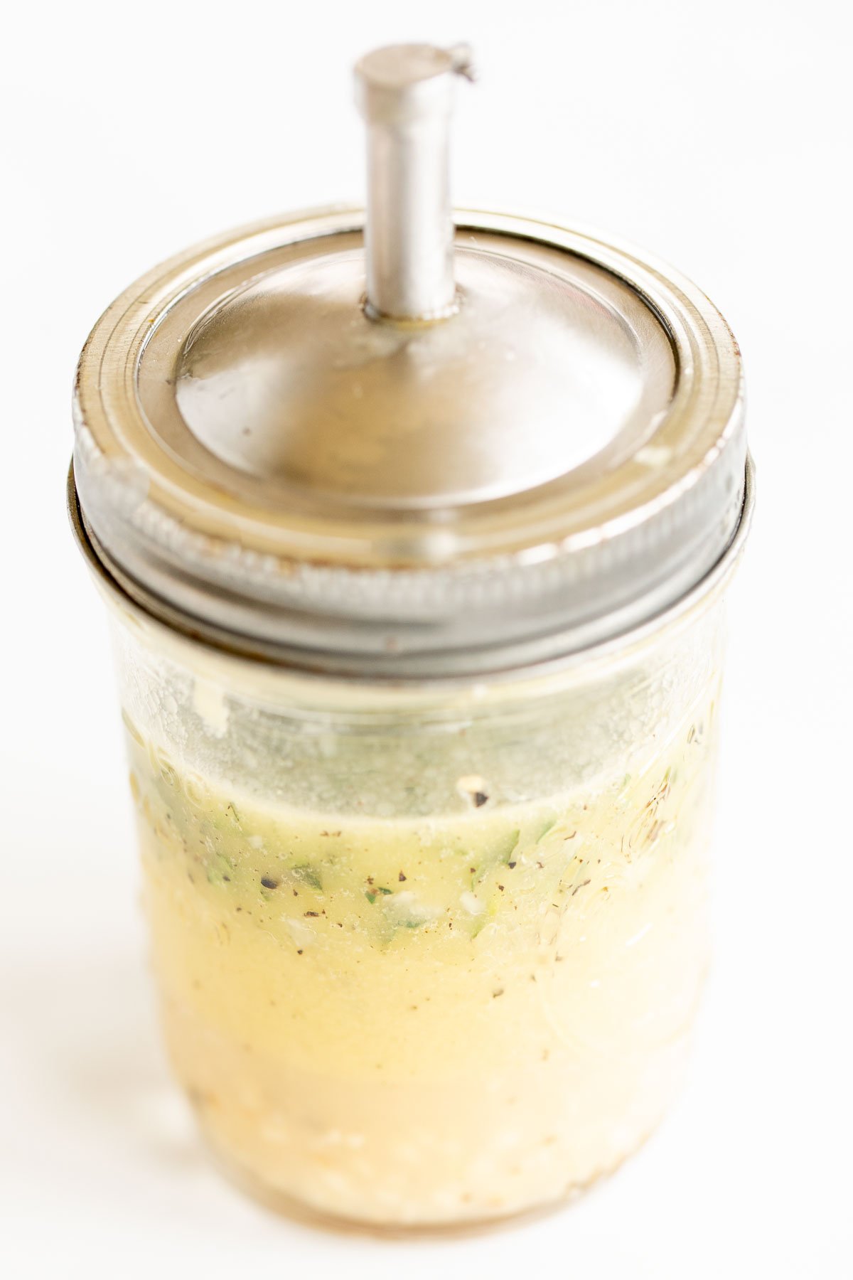 Greek chicken marinade in a glass jar with a silver lid.