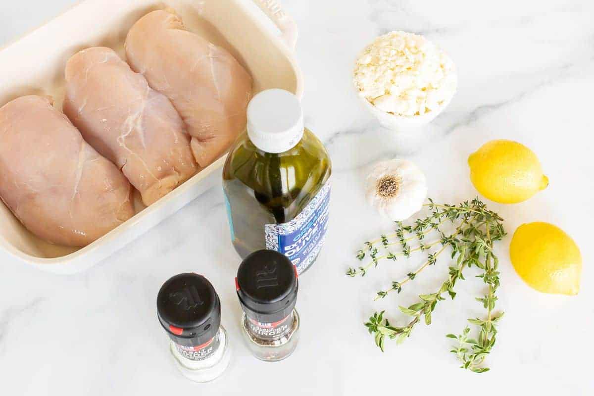 Ingredients for Greek chicken laid out on a marble surface.