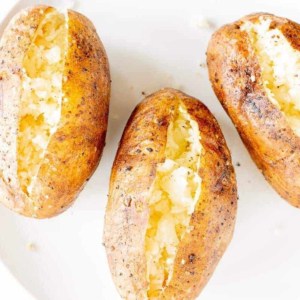 grilled baked potatoes sliced open and placed on a white plate.
